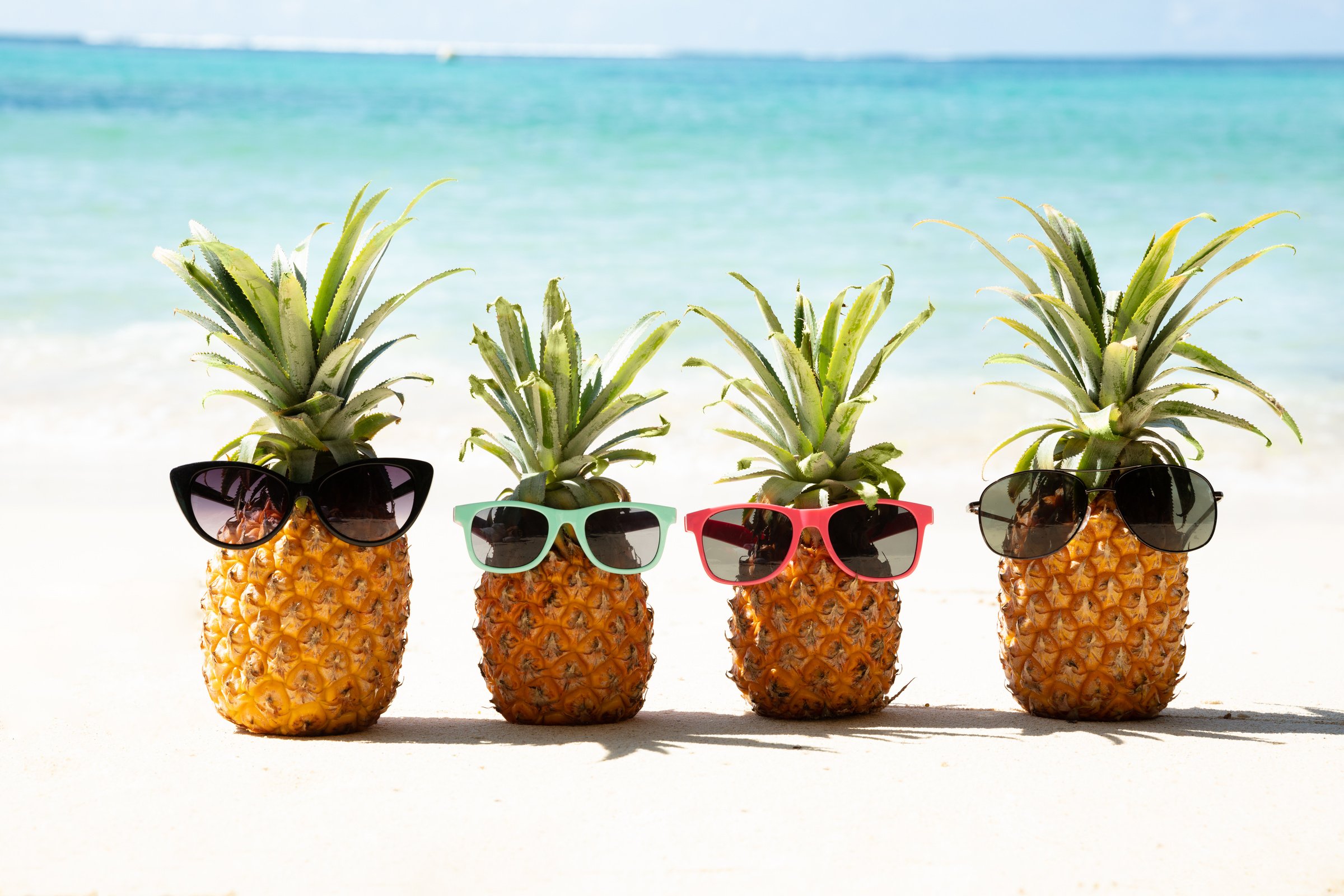 Family Of Pineapples With Sunglasses On Beach